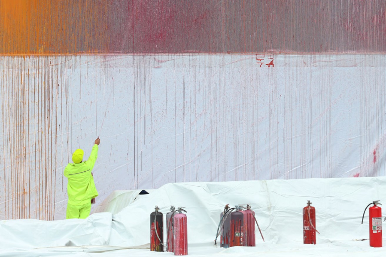 Ash Keating paints a 19m x 7.5m art instillation on the side of the NGV. Photo: AAP