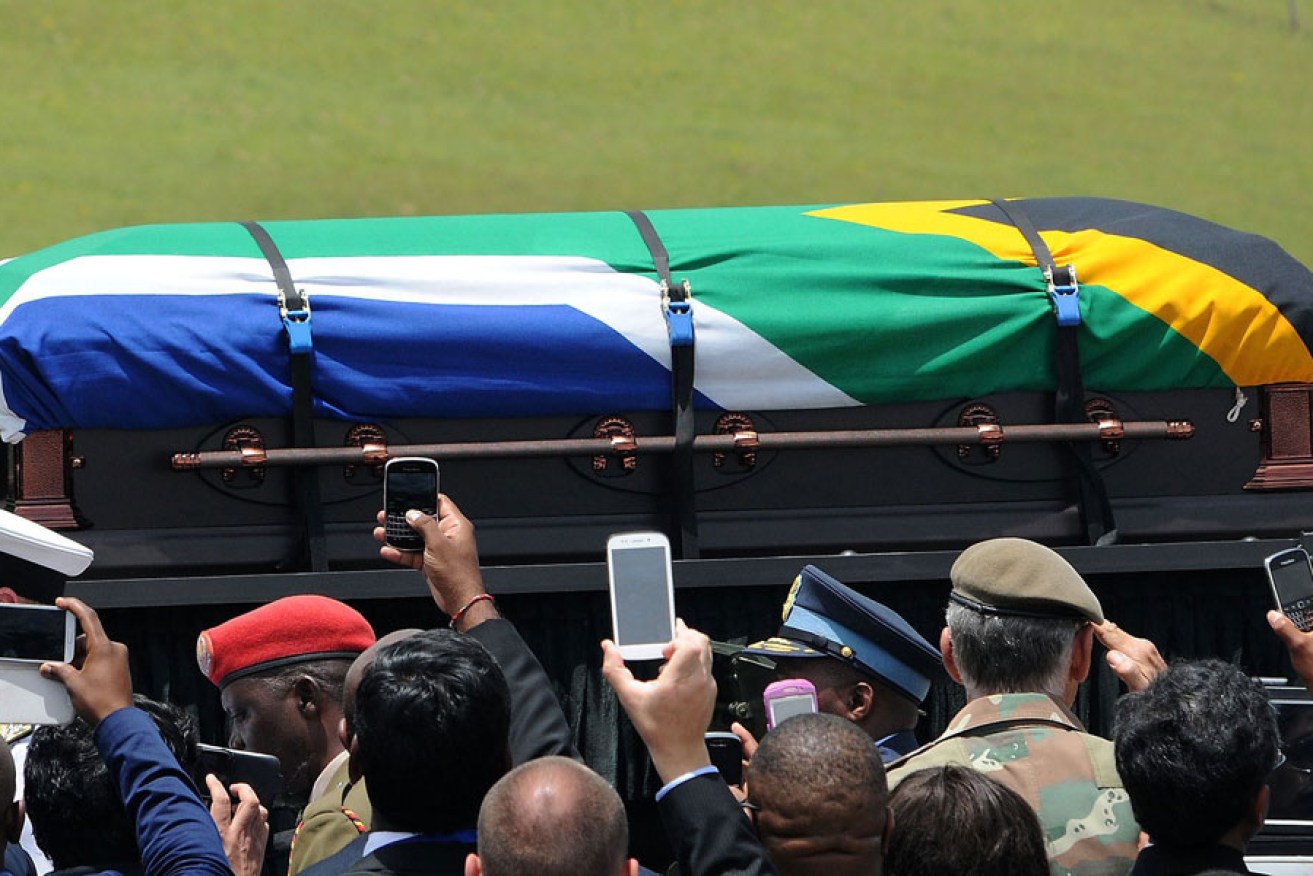People take pictures as the coffin of South African former president Nelson Mandela is carried on a gun carrier for a traditional burial during his funeral in Qunu.