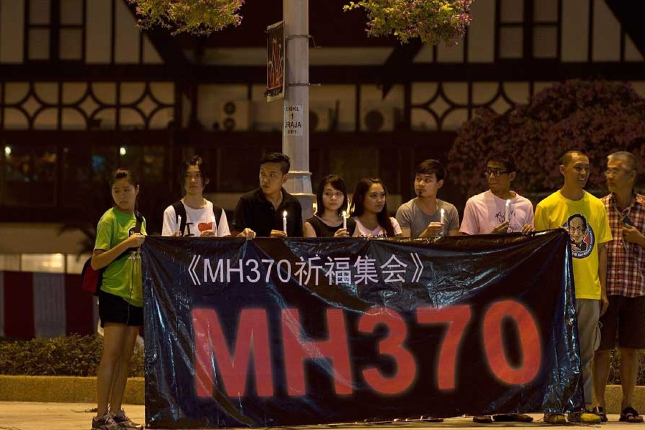 A group of Malaysians hold a banner and candles during a vigil for missing Malaysia Airlines passengers at the Independence Square in Kuala Lumpur.