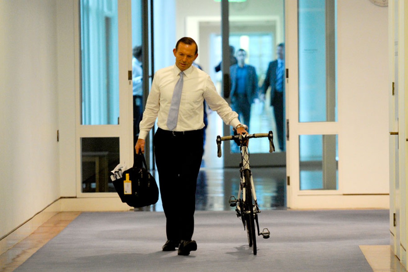 Prime Minister Tony Abbott wheeling his bike into Parliament House.