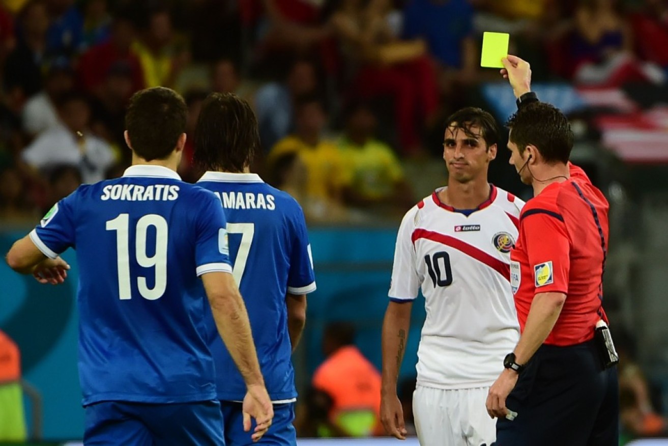 Australian referee Benjamin Williams (R) shows a yellow card to Costa Rica's captain Bryan Ruiz (2nd-R)