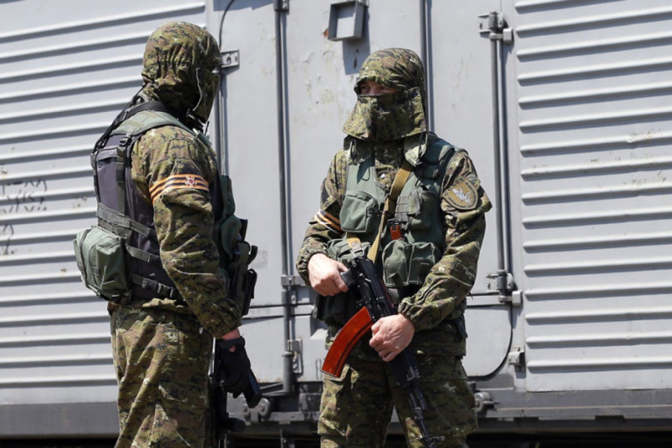 Armed rebels in front of the trains carrying bodies MH17 victims before they left the crash site. Photo: AAP