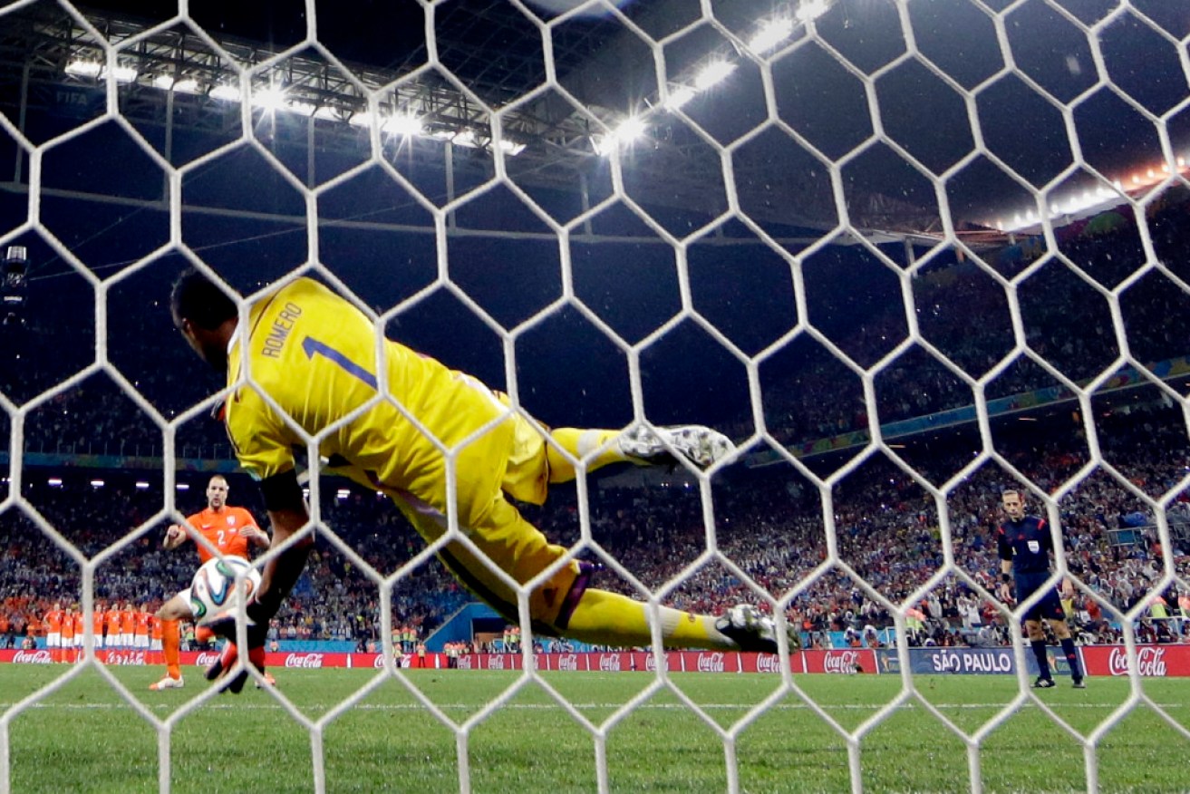 Argentina's goalkeeper Sergio Romero blocks a shot by Netherlands' Ron Vlaar during a penalty shootout