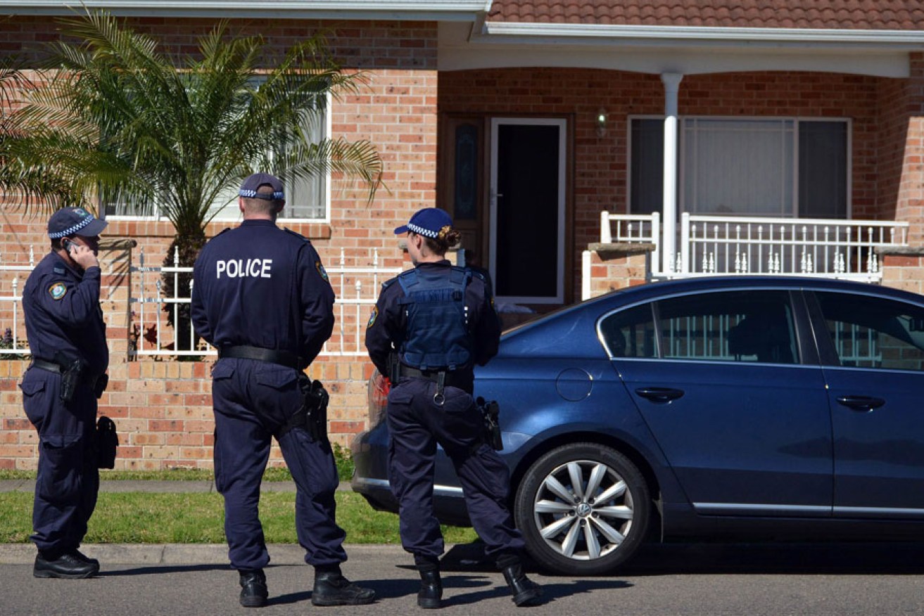 Police stand guard outside a house during a raid in the Guildford area of Sydney.