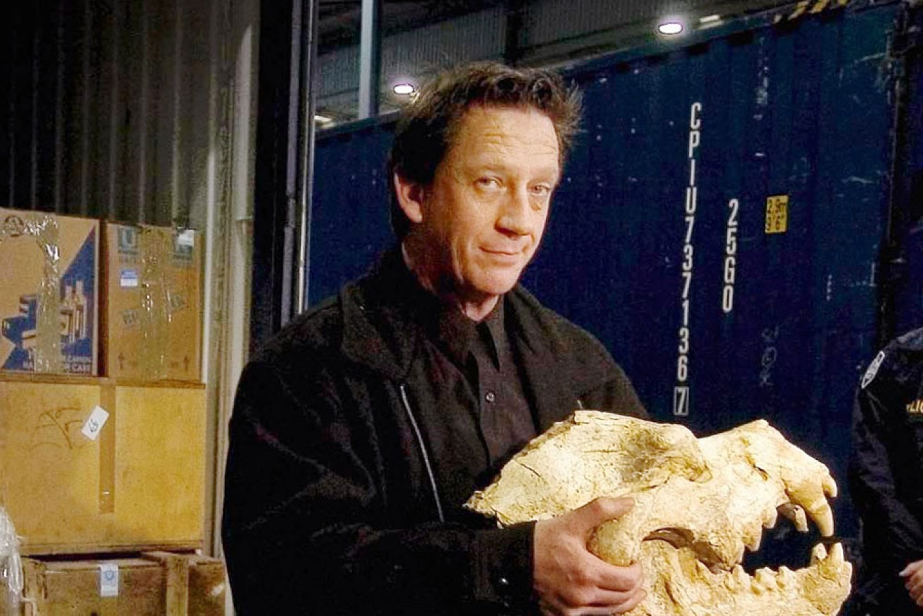 Professor Long with the fossilised skull of a hyena. 
