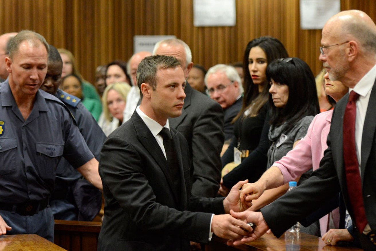 Oscar Pistorius holds the hands of his uncle Arnold Pistorius and family members at an earlier hearing.