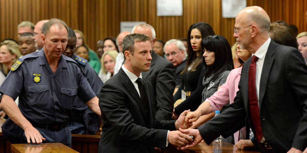 Oscar Pistorius holds the hands of his uncle Arnold Pistorius and family members at an earlier hearing.