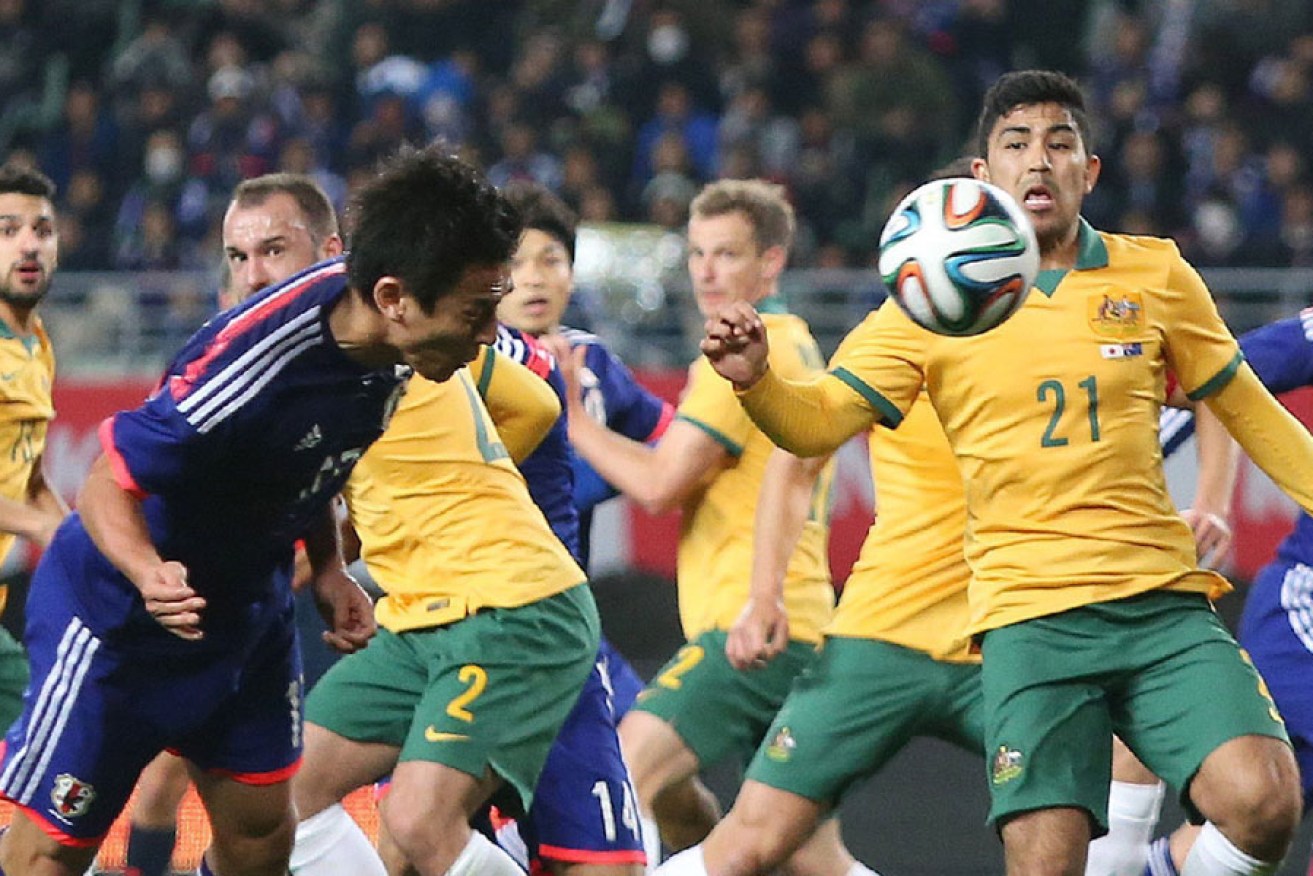 Japan midfielder Makoto Hasebe heads the ball while Australia's forward Massimo Luongo (R) attempts to block.