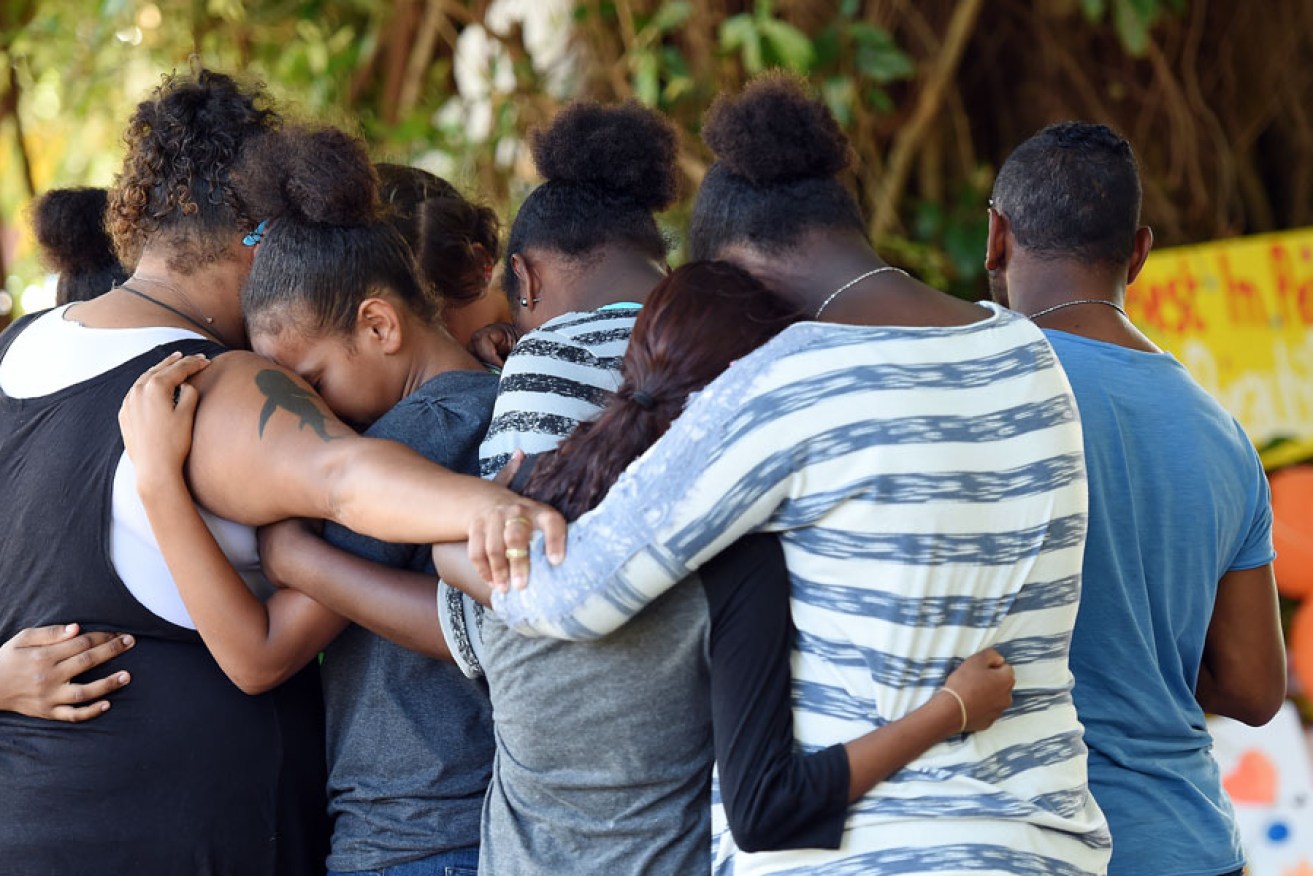 Mourners gather at a floral tribute near a Cairns house in which eight children were murdered. 