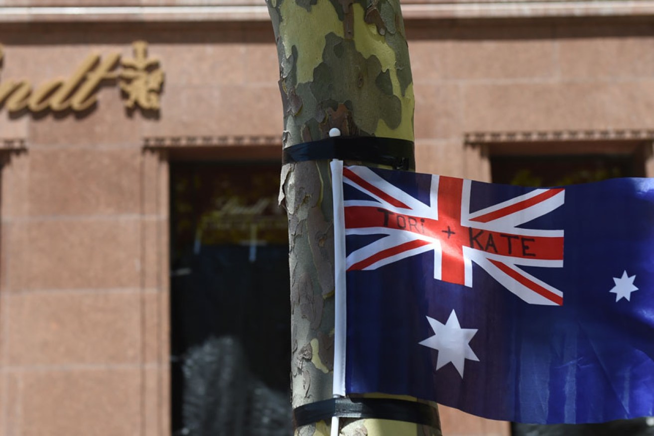 A flag blows in the wind bearing the names of siege victims Tori Johnson and Katrina Dawson at a memorial outside the Lindt Cafe in Sydney in December.