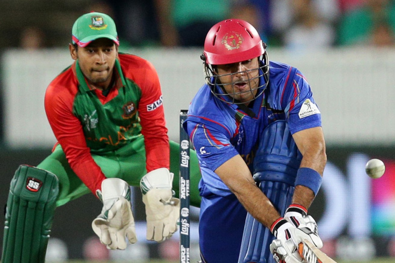 Afghanistan batsman Mohammad Nabi plays a sweep shot as Bangladesh wicketkeeper Mushfiqur Rahim looks on.