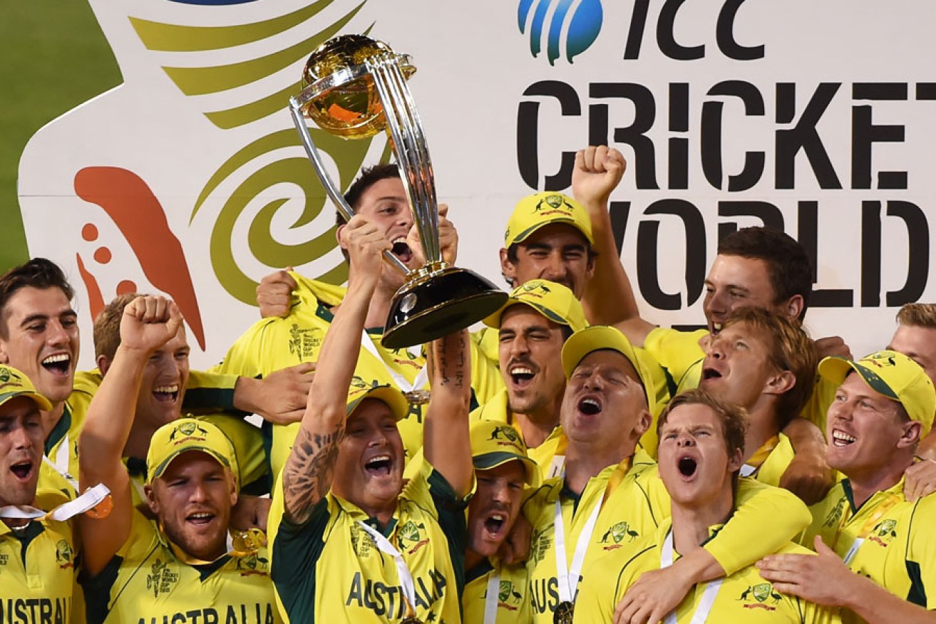 Michael Clarke holds aloft the World Cup trophy, surrounded by his jubilant teammates.