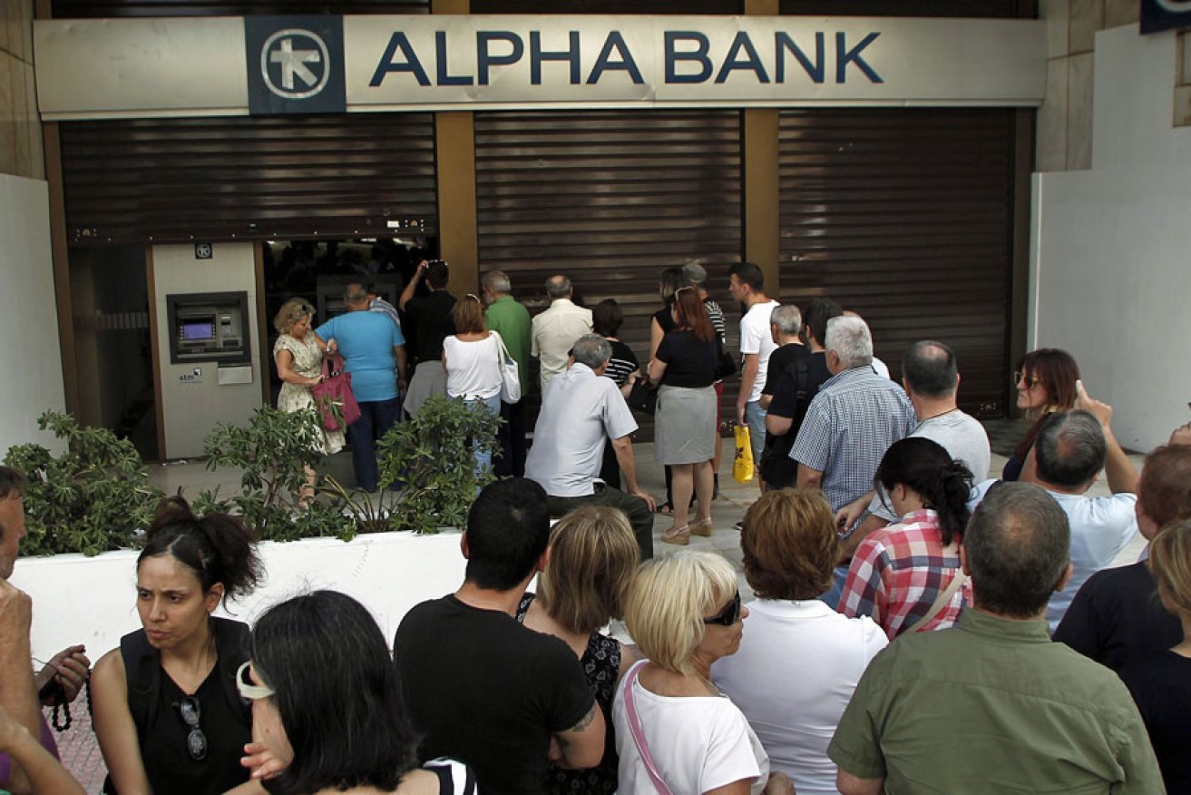 People queue to withdraw money from an ATM at a branch of Greece's Alpha Bank in Athens.