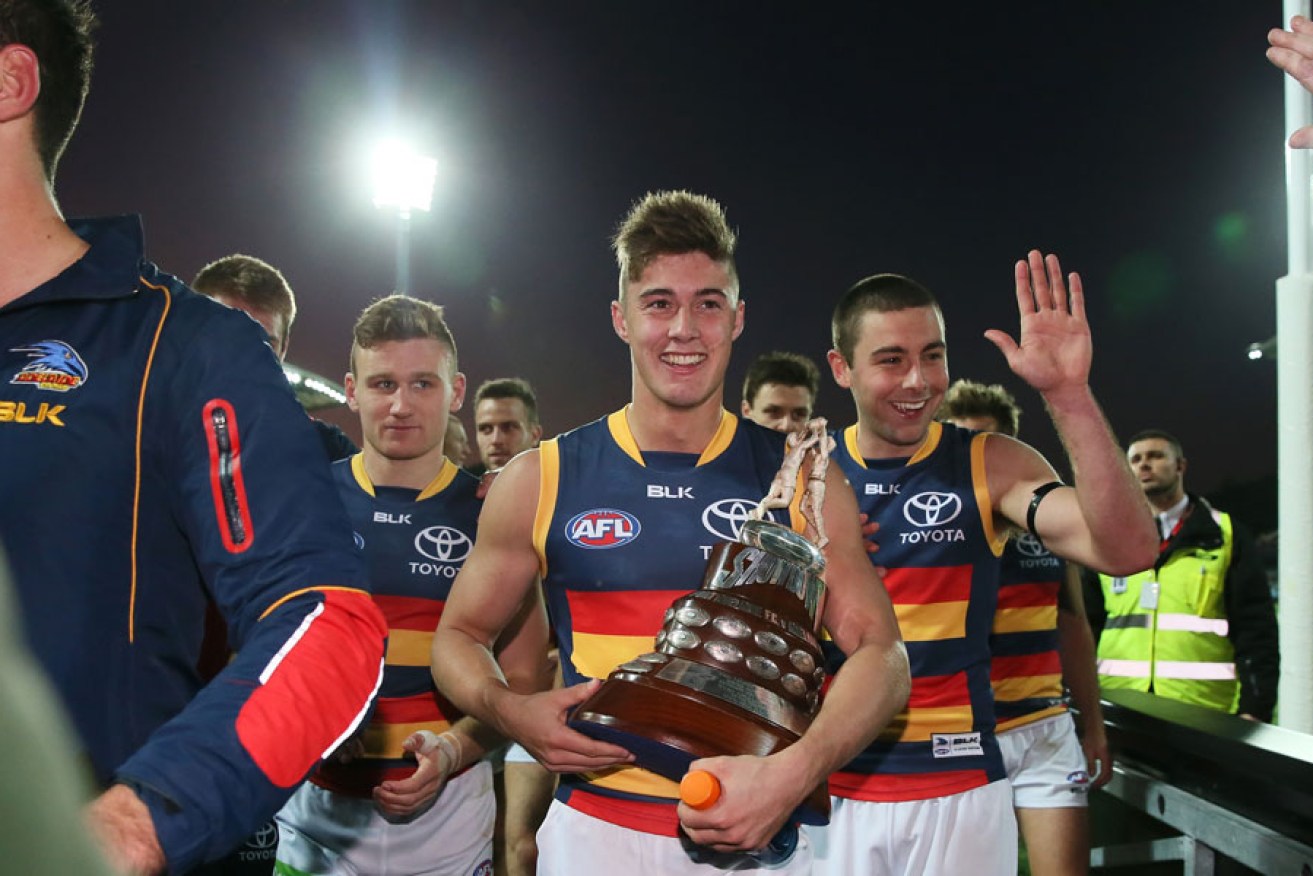 Second-game player Riley Knight leaves Adelaide Oval with the Showdown trophy in his grasp. 