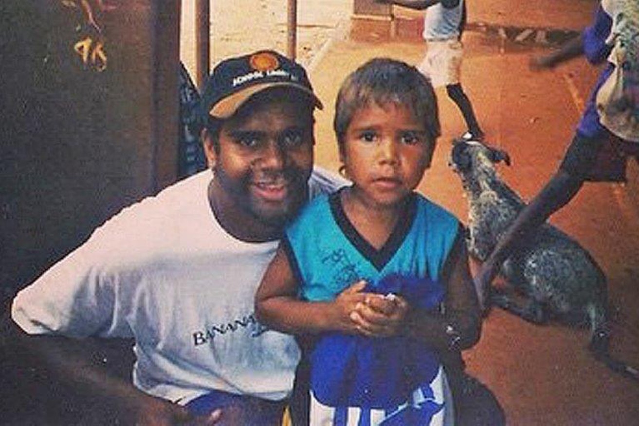 Then-Kangaroos star Byron Pickett with a young boy in the Northern Territory in the late 1990s. The boy, Jake Neade, now plays for Port Adelaide.