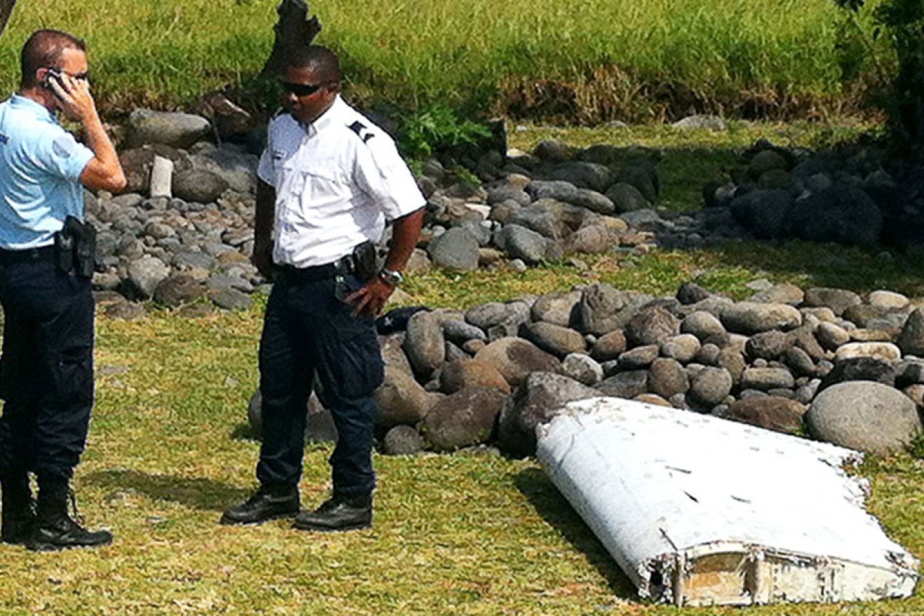A policeman and a gendarme stand next to a piece of debris from an unidentified aircraft found on the Indian Ocean island of La Reunion. AFP photo