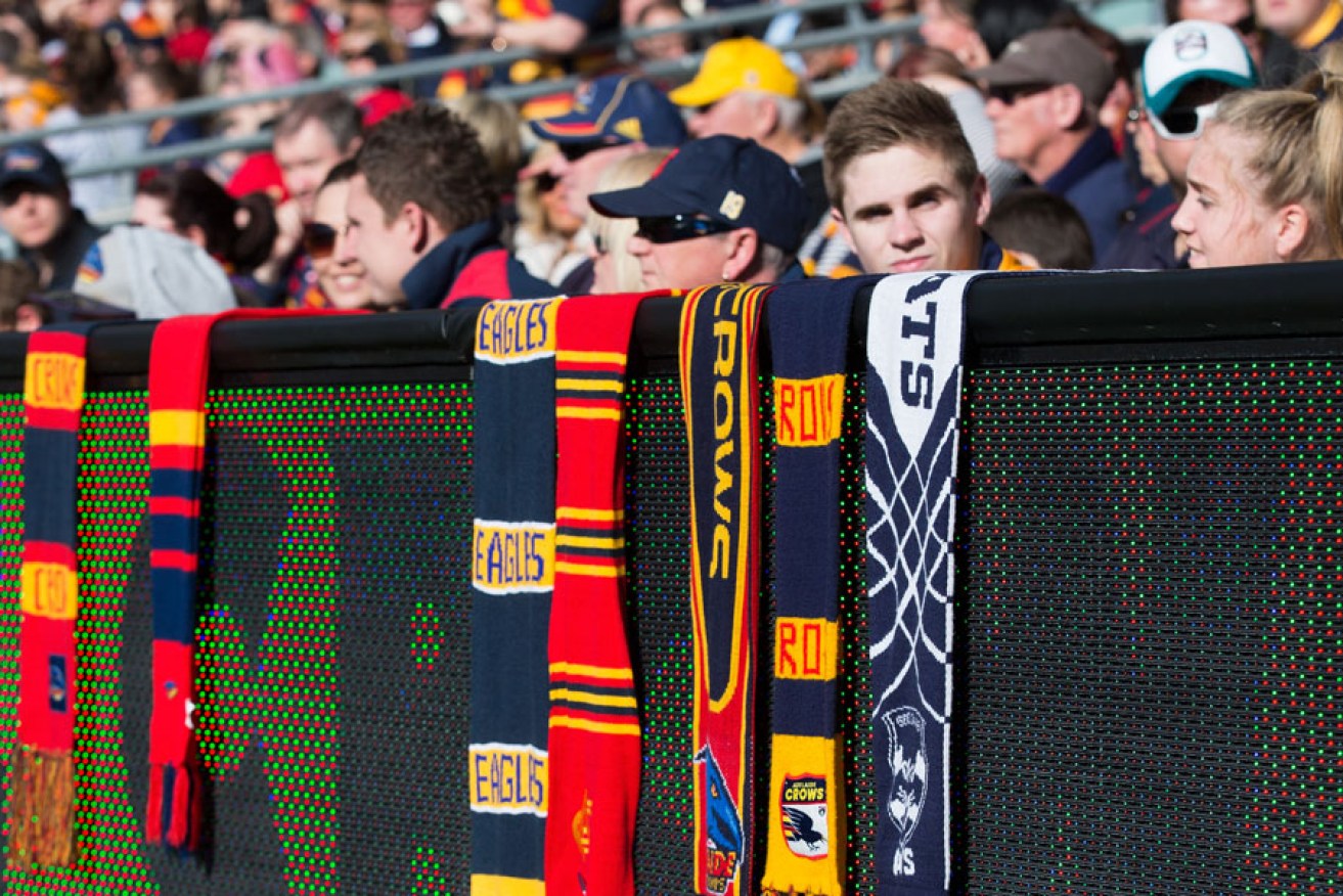 Fans of different clubs hang their scarves on the Adelaide Oval fence during Sunday's tribute to Phil Walsh. AAP image