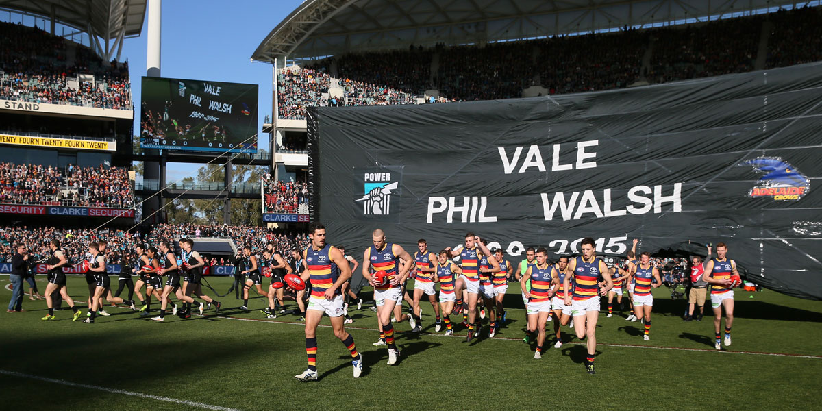 Port Adelaide and Adelaide players go through a joint banner before the Showdown. AAP image