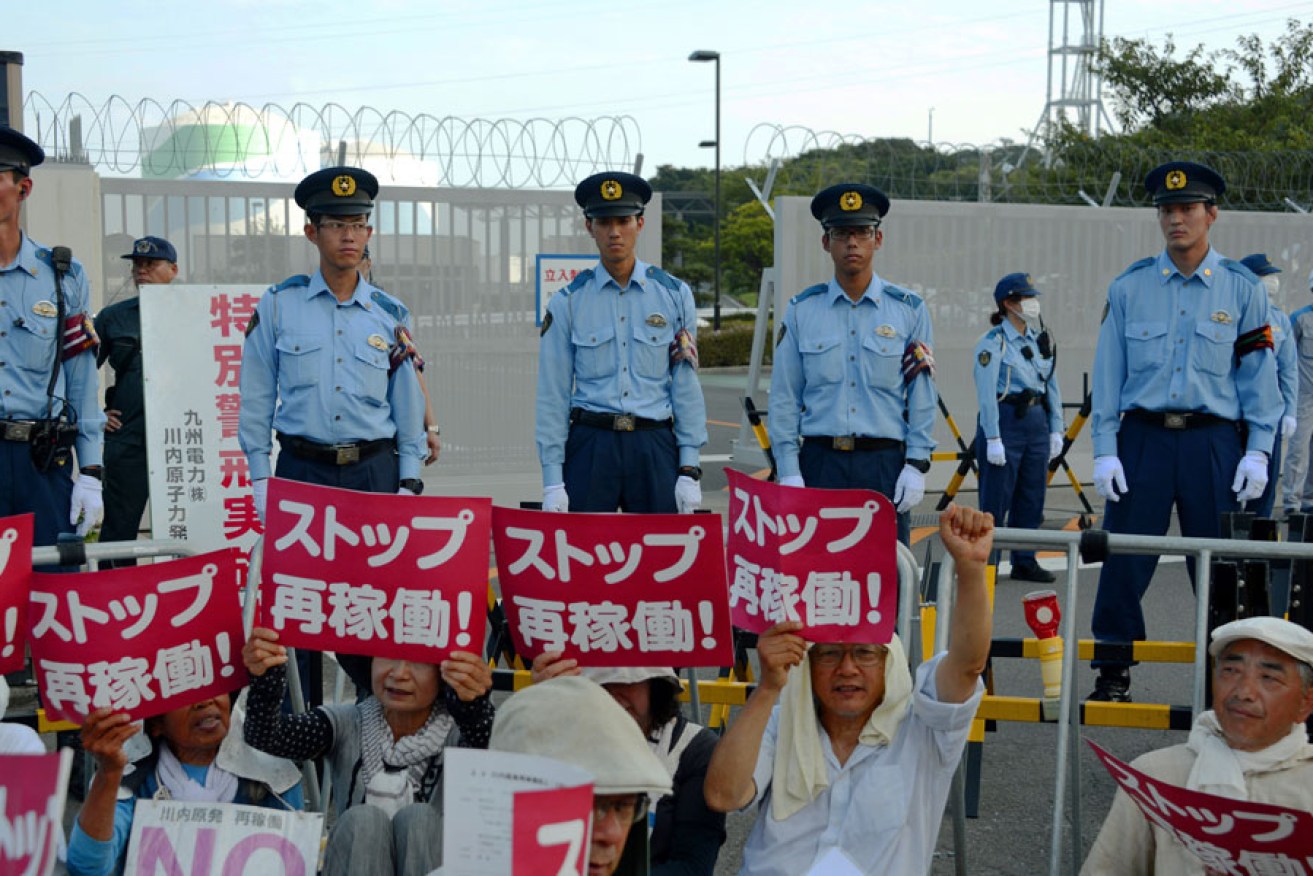 Police officers stand guard as protesters rally against restarting the nuclear reactor at the Kyushu Electric Power Sendai nuclear power plant. 