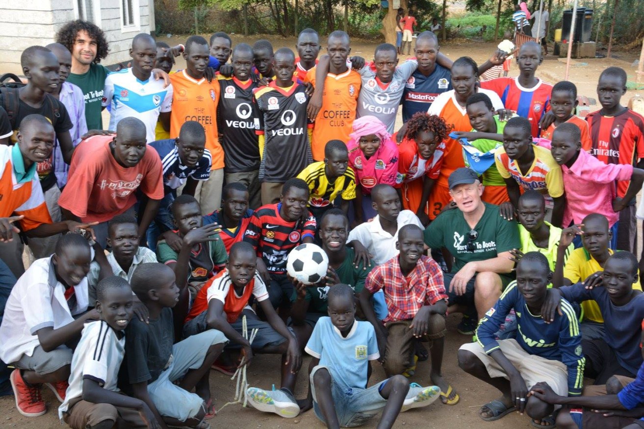 Ian Smith (in green T-shirt and cap) with Awer Mabil (centre, holding soccer ball) and Osama Malik (top left, green T-shirt) with refugees at the Kakuma camp earlier this year. Image supplied