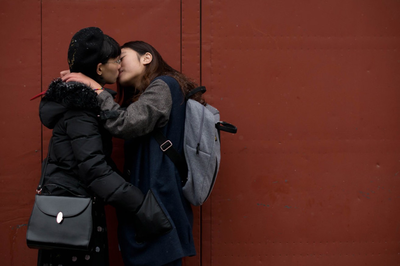 Two women kiss outside a registry office in Beijing in a bid to draw attention to discrimination against LGBTQ people. Photo: AAP