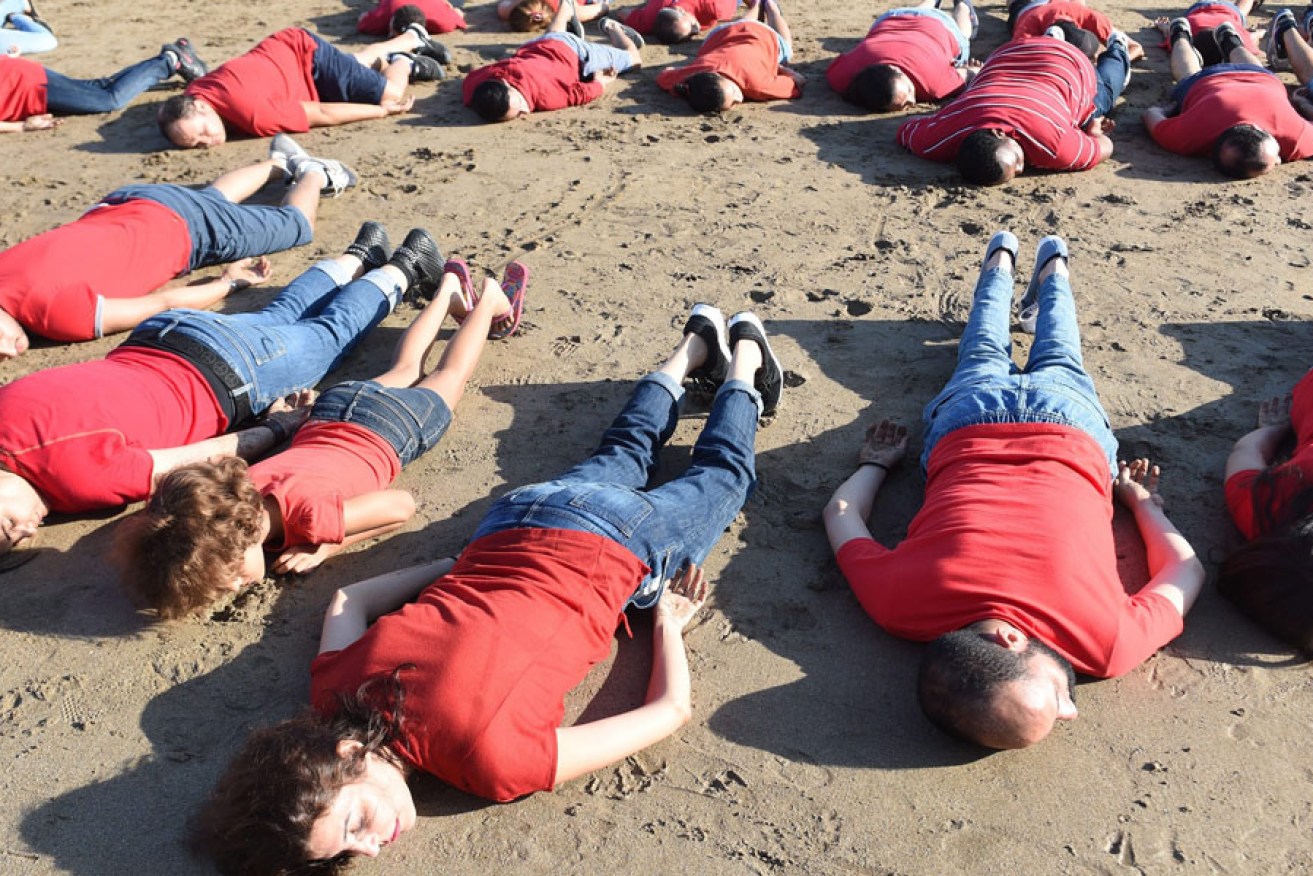Moroccans adopt the position of the lifeless body of Syrian three-year-old Aylan Kurdi, during a rally to pay tribute to the little boy. EPA image