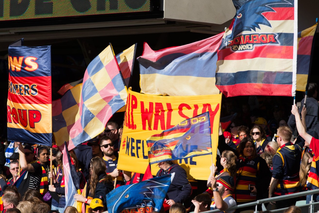 Crows supporters embrace the club's slogan at an Adelaide Oval memorial for slain coach Phil Walsh on July 5.