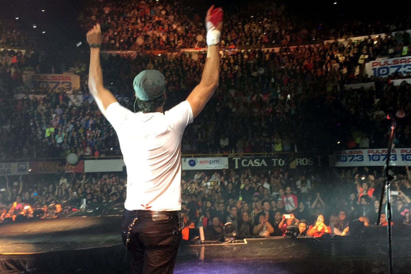 Spanish pop star Enrique Iglesias holds up his bloodied hand cut by a drone.