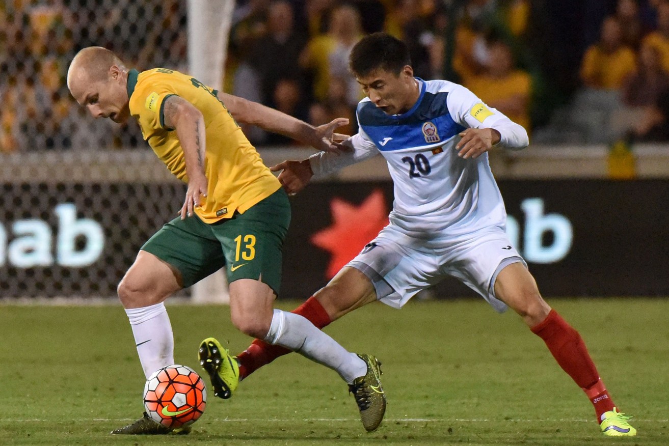 Aaron Mooy fights for the ball with Duishhebekov Bahtiyar during last night's world cup qualifier.