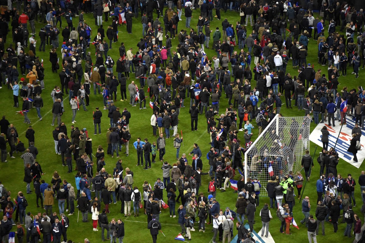 Football fans gather in the field as they wait for security clearance to leave the Stade de France in Saint-Denis, north of Paris, after the friendly football match France vs Germany on November 13, 2015 following shootings and explosions near the stadium and in the French capital. A number of people were killed and others injured in a series of gun attacks across Paris, as well as explosions outside the national stadium where France was hosting Germany. AFP PHOTO / FRANCK FIFE
