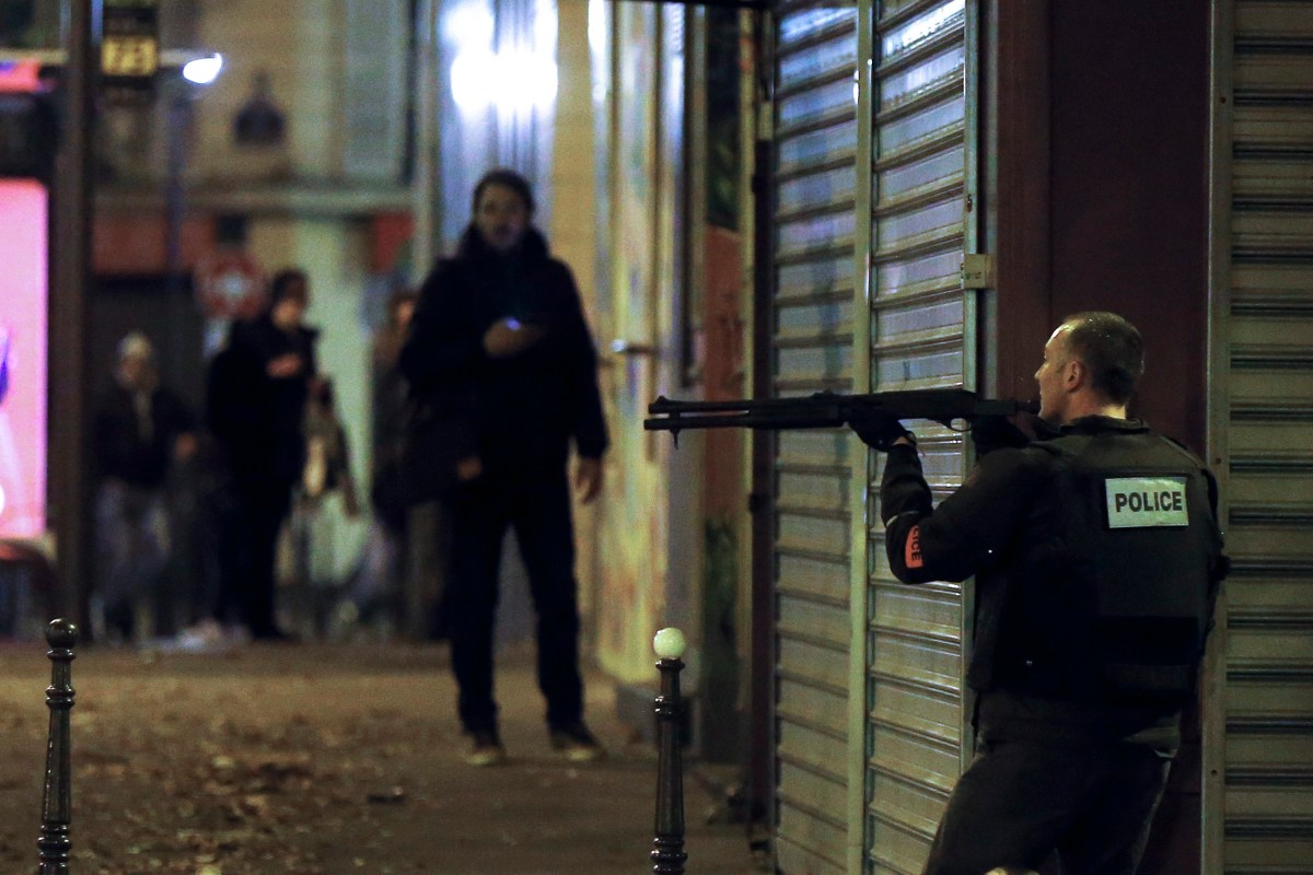 A French police officer takes cover while on the lookout for the shooters who attacked the restaurant 'Le Petit Cambodge' earlier tonight in Paris, France, 13 November 2015. EPA/ETIENNE LAURENT