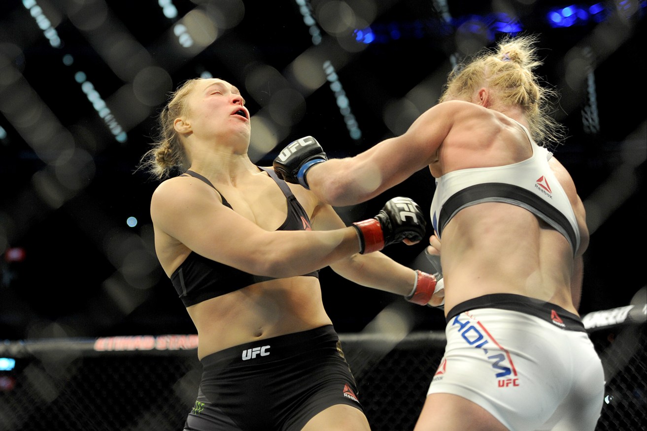 Holly Holm collects defending champion Ronda Rousey (left) in the Women's Bantamweight Bout during UFC 193 at Etihad stadium. AAP Image/Joe Castro