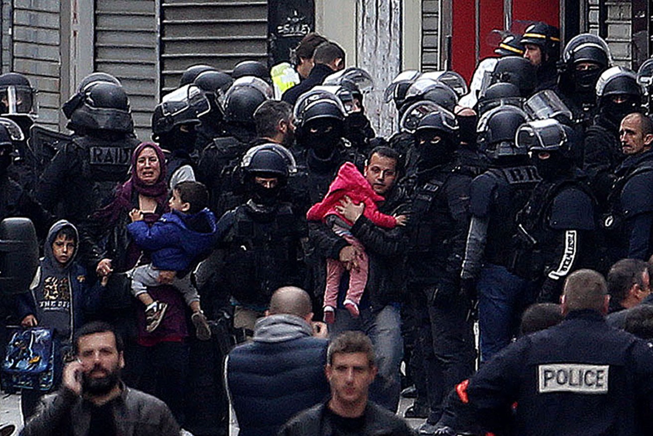 A family is escorted away during a raid on an apartment in the Saint-Denis suburb of Paris. Image: Steve Parsons/PA Wire