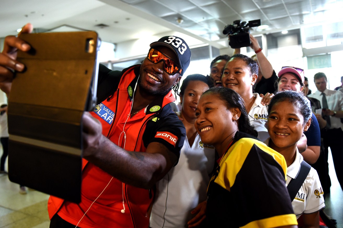 Gayle posed for photographs with the PNG Womens Cricket Team as he arrived at Melbourne Airport ahead of his media conference apology. Photo: Tracey Nearmy, AAP.