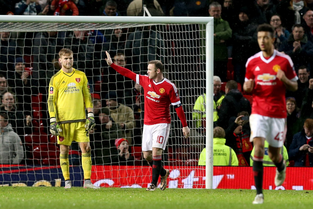 Sheffield United goalkeeper George Long stands dejected as Wayne Rooney celebrates scoring ManU's first goal of the game. Photo: Martin Rickett, PA Wire.