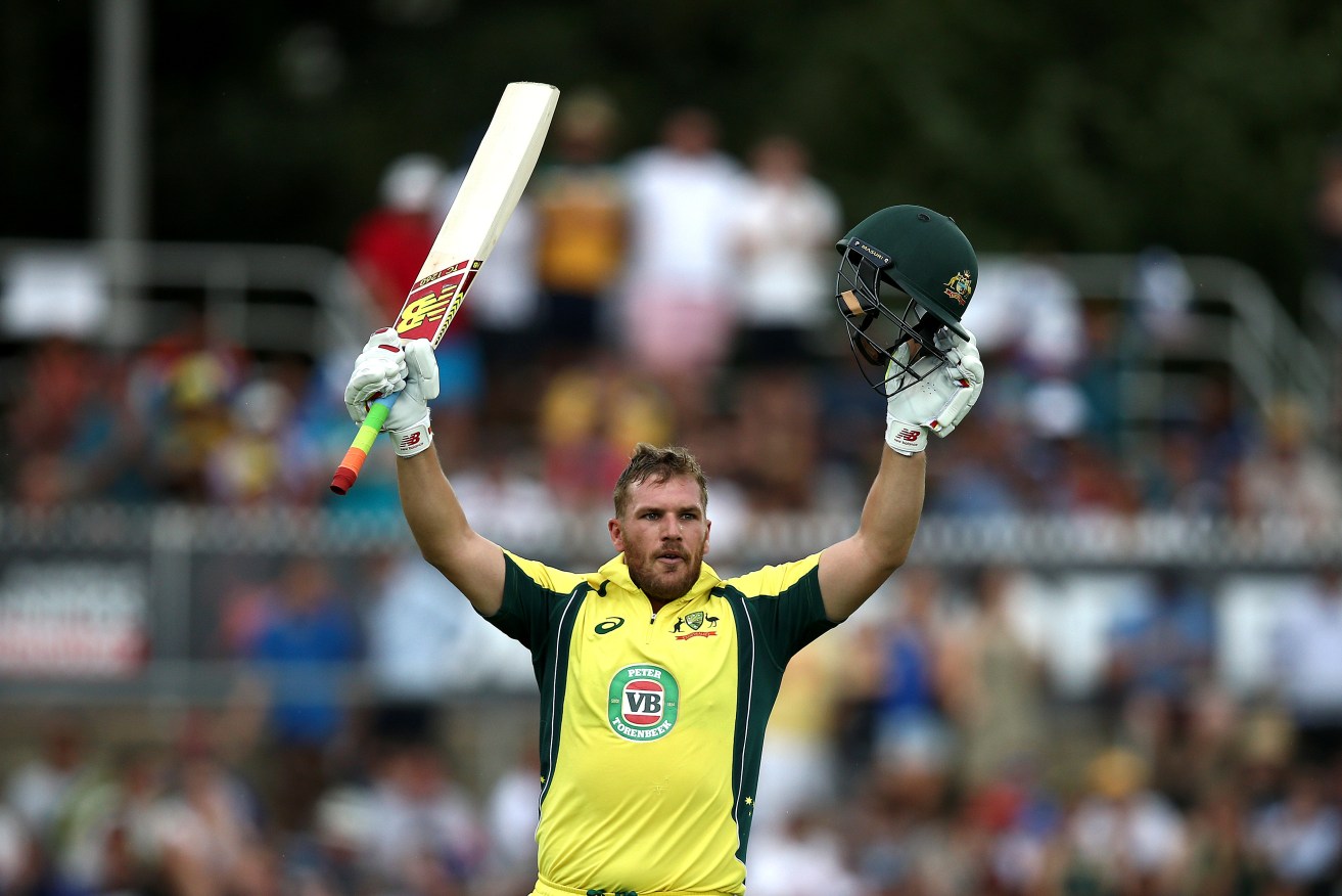 Aaron Finch celebrates a ton against India in January. Now he's carrying the drinks. Photo: Rob Griffith, AP.