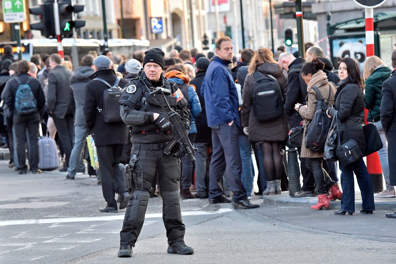 People queue for buses behind a policeman in Brussels. Photo: AP/Martin Meissner)