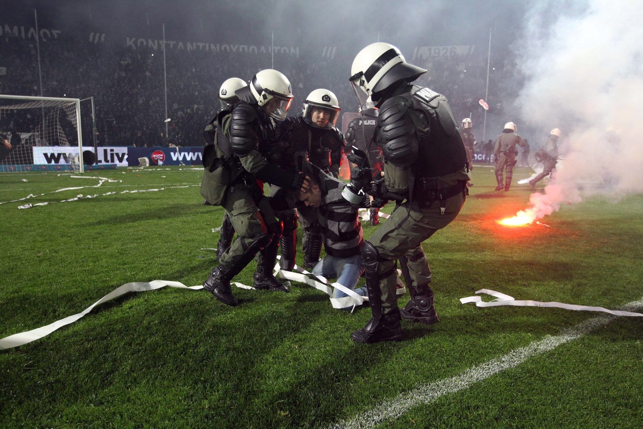 Greek riot policemen detaining a PAOK supporter during riots that broke out during a PAOK vs Olympiacos match in Thessaloniki, north Greece. Deputy Sports Minister Stavros Kontonis called off the Greek Cup, citing numerous violent incidents that have plagued recent matches between football clubs.  Photo: SOTIRIS BARBAROUSIS, EPA.