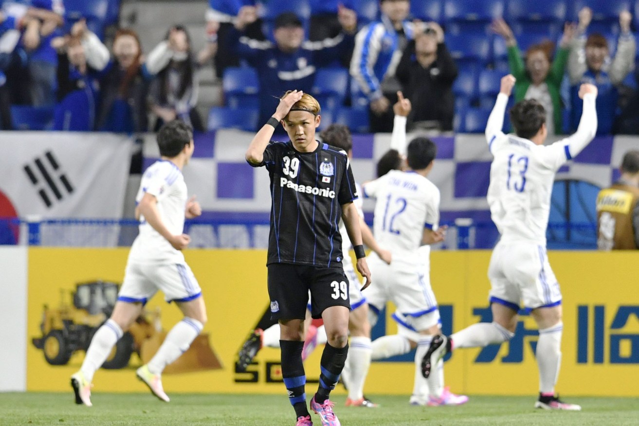 South Korea's Suwon Samsung Bluewings FC players celebrate after their side's second goal while Gamba Osaka striker Takashi Uami looks forlorn. The loss sent Gamba crashing out of the ACL in the first round - a boon for Sydney FC.