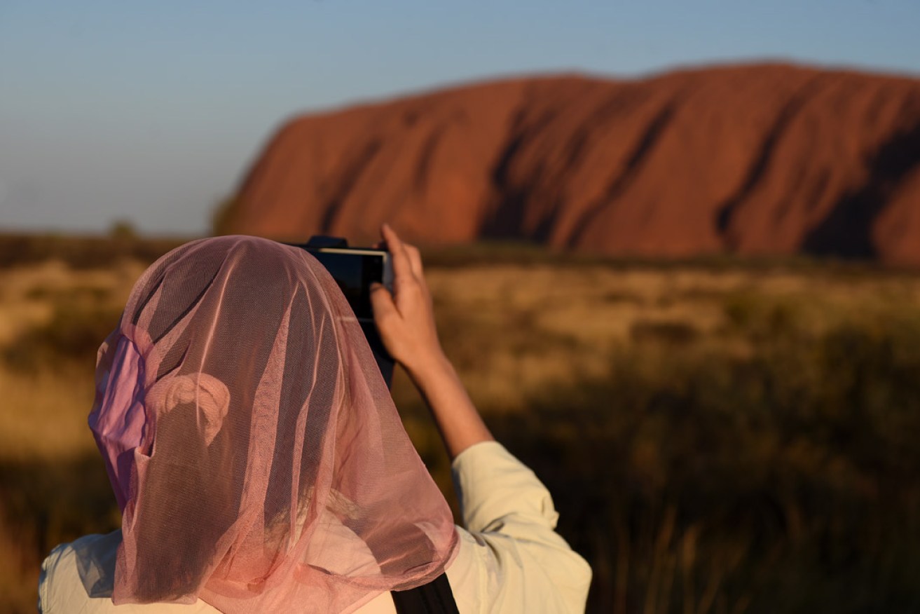 A tourist takes photos of Uluru. Photo: AAP
