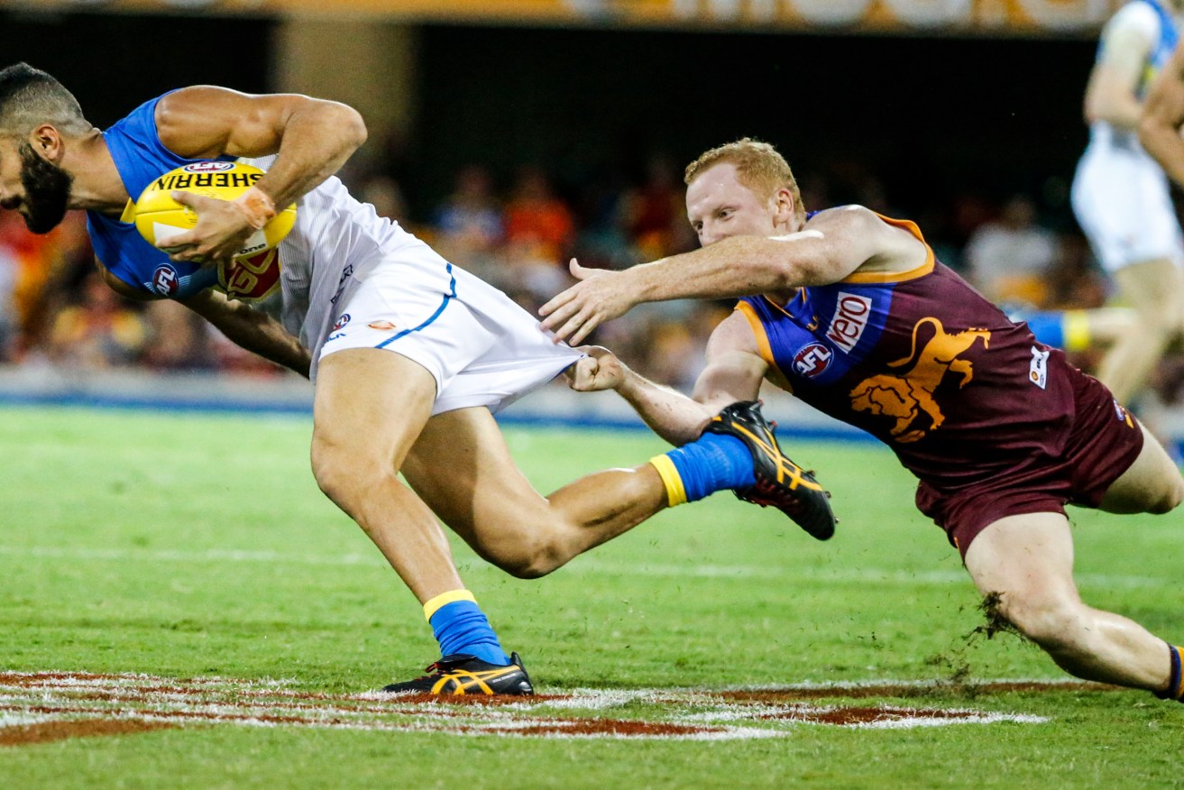 ONLY ROOM FOR ONE TEAM IN QUEENSLAND? Adam Saad of the Suns is tackled by Brisbane's Josh Green. Photo: Glenn Hunt, AAP.