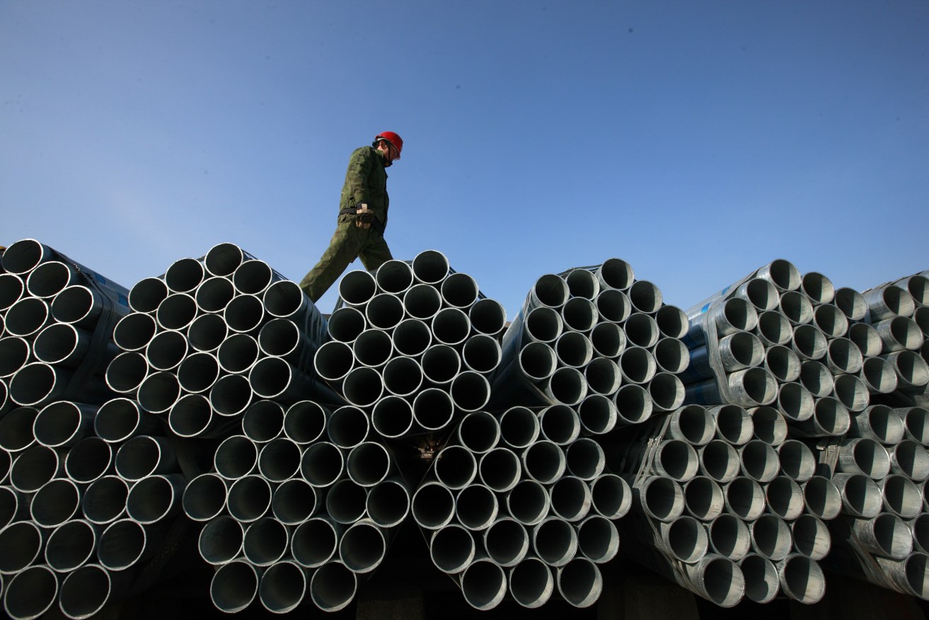 A Chinese worker walks on steel pipes at a factory in Huaibei city. AP photo