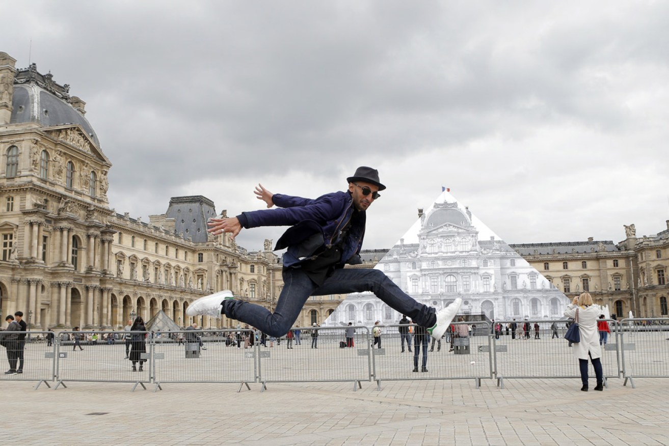 JR poses in front the Louvre Pyramid. Photo: AP 