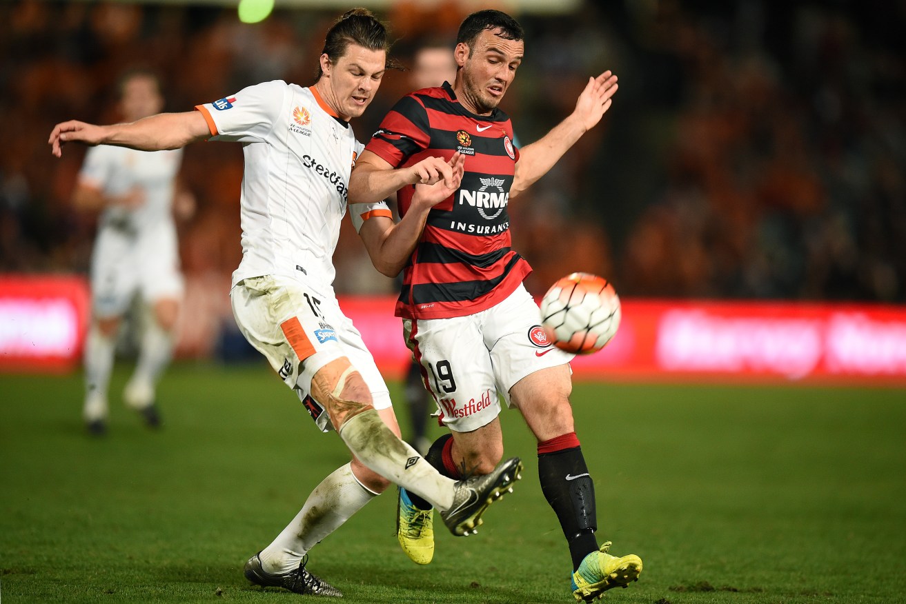 Former Roar defender James Donachie tackles Mark Bridge of the Wanderers during their heart-stopping A-League semi-final. Photo: Dan Himbrechts, AAP.