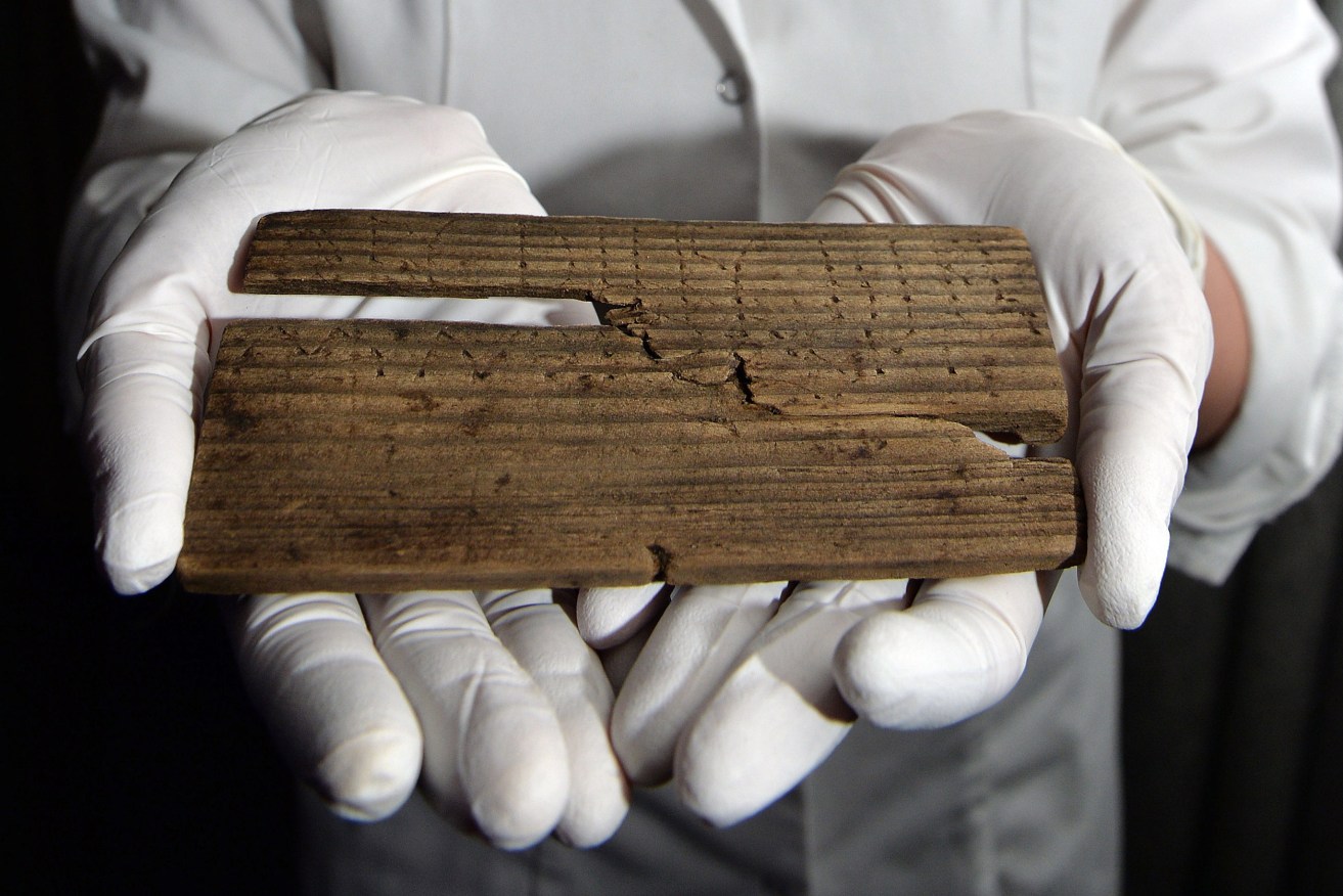 Luisa Duarte, a conservator for the Museum of London, holds a piece of wood with the Roman alphabet written on it. Photo: John Stillwell/PA