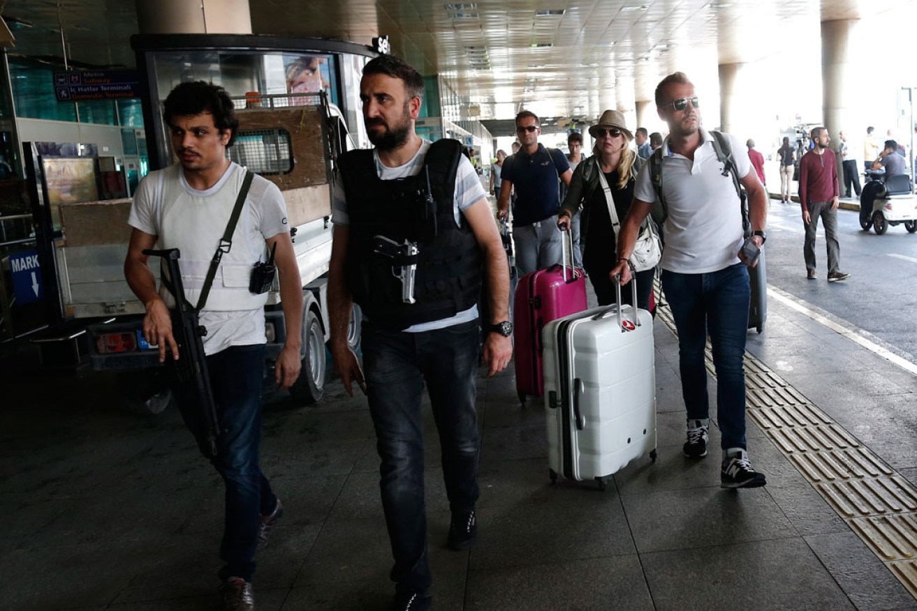 Armed Turkish policemen patrol as tourists arrive at the reopened airport in Istanbul. Photo: AAP