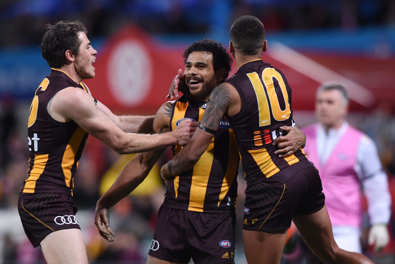 Cyril Rioli is congratulated by Isaac Smith and Brad Hill after kicking the winning goal against Sydney. Photo: Paul Miller, AAP.