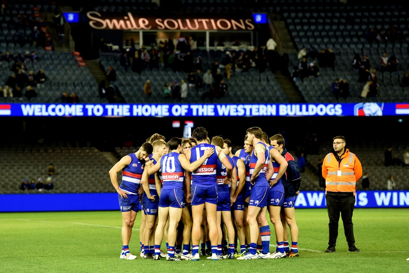 Bulldogs players console each other before walking off the field after Saturday's devastating defeat. Photo: Tracey Nearmy, AAP.