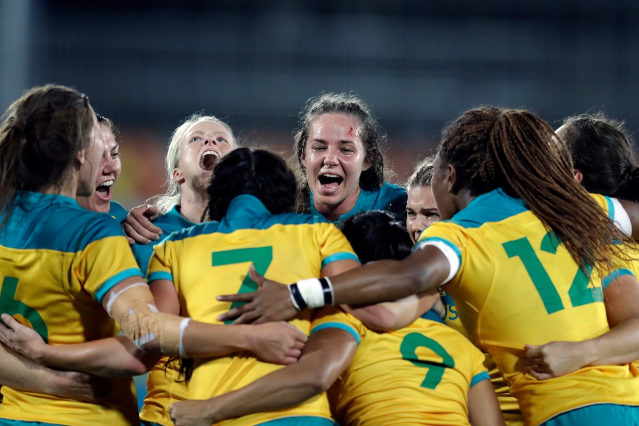 Australia's players celebrate after winning the women's rugby sevens gold medal match against New Zealand. Photo: Themba Hadebe, AP.