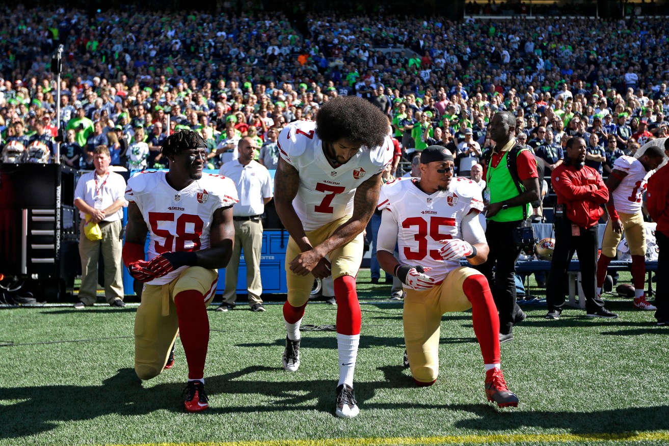 San Francisco 49ers Eli Harold (58), Colin Kaepernick (7) and Eric Reid (35) drop to a kneeling position at the beginning of the national anthem before an NFL football game against the Seattle Seahawks on the weekend. Photo: Ted S. Warren / AP